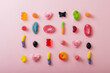 Directly above view of differently shaped multi colored sugar candies arranged on pink background