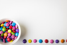 Directly Above View Of Copy Space By Colorful Candy Trail And In Bowl On White Background
