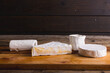 Brie cheese of various shape on wooden table, copy space