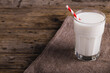 High angle view of milk in glass with straw on wooden table, copy space