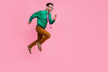 Wall Mural - Full length photo of hurrying pretty man dressed green shirt eyewear jumping running fast empty space isolated pink color background