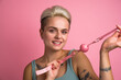 Woman posing with pink silicone ball gag for her mouth with breathing holes and leather belt