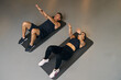 Man and woman having workout together, both doing sit ups on the gym floor