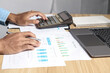 © Sai - Businessman using calculators and laptops to calculate financial figures working in the office. Financial accounting concept