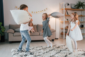 Pillow fight at birthday party. Group of children is together at home at daytime