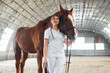 Smiling and posing for a camera. Standing together. Female doctor in white coat is with horse on a stable