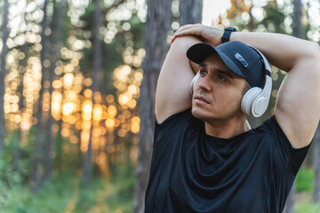 A young man training in the forest during the golden hour stretching and measuring pulse while enjoying nature