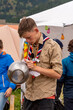 Boy scout cleaning kitchenware in a campsite