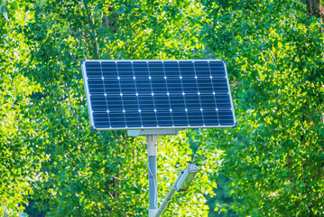 street lamp, powered by the sun, against the background of green trees, selective focus