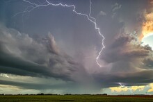 Scenic Shot Of Lightning From A Brewing Storm Striking Over A Wide Green Field