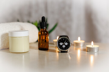 lotion with watch and essencebottle with candles and towel