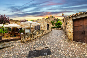 Wall Mural - The medieval Spanish village of Pals, Spain, with a sidewalk cafe on it's cobbled damp streets after a summer rainstorm near the Costa Brava coast.