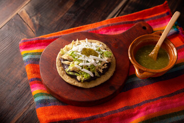 Wall Mural - Sopes de Pollo. Traditional homemade Mexican appetizer prepared with fried corn dough covered with refried beans, green or red sauce, lettuce, cheese, onion and shredded chicken