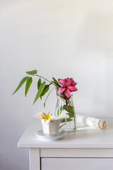 Poster - Plumberia rumba in a coffe cup, eucalyptus branch in a vase and cup of coffee on a white table against a wall with two frames. Ready layout. Vertical frame. Space for text