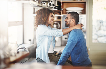 Wall Mural - Young, in love and happy couple talking, hugging and having fun in a kitchen at home. Lovers embracing, enjoying time together while bonding. Partners being affectionate and having a romantic moment