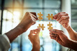 Group of business people holding puzzle pieces. Professionals connect and collaborate together inside office building. Closeup of hands, and team working together on a new strategy for success.