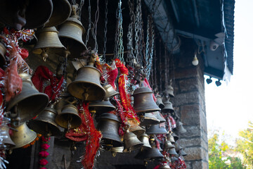 Temple bells tied outside ancient temple. Religious, religion, hindu, hinduism, people, worship, faith, holy, wish, knot, tie, god, goddess, lord, Vishnu, Shiva, pilgrimage, prayer, pilgrims, antique.