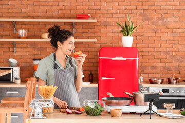 Sticker - Young woman with bell pepper cooking from video tutorial in kitchen