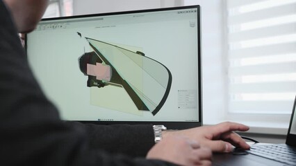 An unrecognizable man develops the design of a part. An engineer works with a 3D model in a design program.