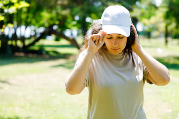 Athletic young woman wearing a white baseball cap in the woods