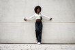 © fotofabrika - Black woman with afro hair posing in front of a gray concrete wall