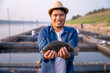 Aquaculture farmer hold quality tilapia yields in hand, guaranteeing integrity in organic bio-aquaculture. Fish is a high-quality protein food source. Commercial aquaculture in the Mekong River.