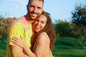 Wall Mural - Happy couple covered with colorful powder dyes outdoors. Holi festival celebration