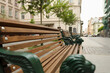 View of wooden bench with wrought legs on city street