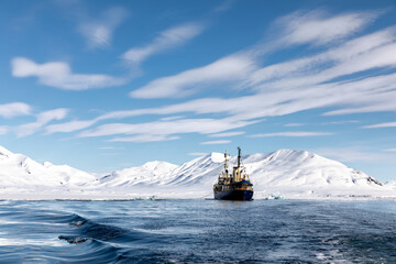 Wall Mural - icebreaker at anchor in the arctic waters of svalbard. crisp blue sky and snowy mountain background.