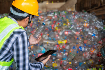 A recycling Analyst looking at plastic bottle ofr recycling waste To proceed to the next process. A workers work on recycle waste at recycling factory.