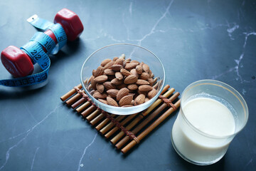 Wall Mural - dumbbell, almond nut and milk on black background 