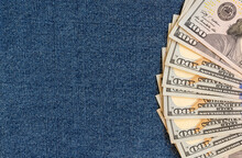 A Stack Of Money On A Background Of Denim. Banknotes Are Partially Visible.