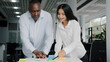 © Yuliia - Two colleagues african and arab businesspeople co-workers writing tasks on sticky notes brainstorming organizing work together managing paperwork in office using colorful memo stickers show thumb up