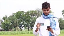 Portrait Of Young Farmer Making Online Payment Through Internet Banking At Agriculture Field.
