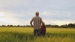 © Acronym - Farmer and his son in front of a sunset agricultural landscape. Man and a boy in a countryside field. Fatherhood, country life, farming and country lifestyle.