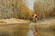Cyclist crosses a stream with his bike and churns up the water.