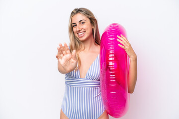 Wall Mural - Young caucasian woman holding air mattress donut isolated on white background saluting with hand with happy expression