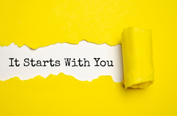 IT STARTS WITH YOU. words. text on yellow paper on torn paper background