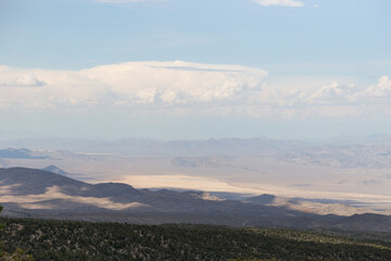  Mountain range hiking trail with cloudy view of dry lake bed once used as atomic bombing test range in the distance
