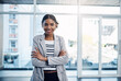 Confident, proud and professional young black business woman folding her arms and smiling in a modern office. Portrait of African American leader looking powerful, successful standing in power stance