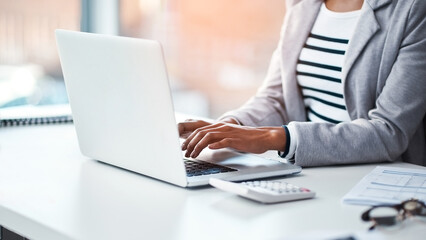 Canvas Print - Female accountant typing on a laptop in her office or doing research on the internet while sitting at a desk. Closeup of a financial advisor working on a project or business proposal at her workplace