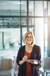 © Daniel Laflor/peopleimages.com - Confident manager, leader or boss typing on a tablet and standing in her creative office at work. Portrait of a smiling, happy and positive business woman ready for success in her startup company