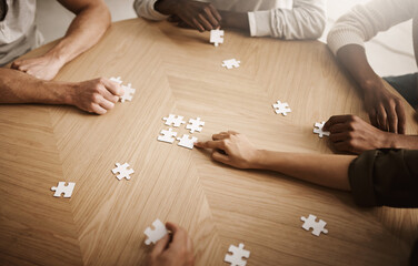 Poster - Friends hands solving a puzzle in a group collaboration together as a team on wooden table indoors. Diverse colleagues using teamwork and support to help each other to find a smart solution close up