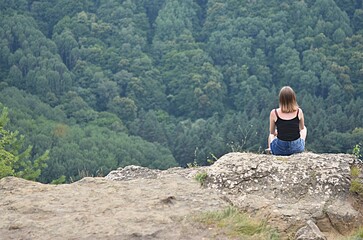 a girl on top of a rock looks at the mountains of the North Caucasus. Bermamyt Plateau. The concept of rest, vacation, freedom