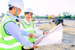 Engineer construction standing see plan paper at the construction site.