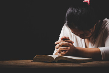 christian woman hand on holy bible are pray and worship for thank god in church with black background, concept for faith, spirituality and religion