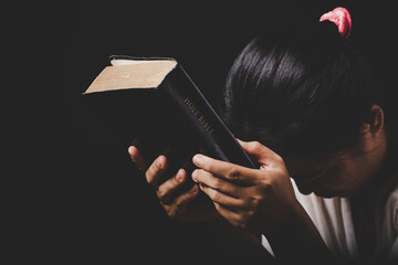 christian woman hand on holy bible are pray and worship for thank god in church with black background, concept for faith, spirituality and religion