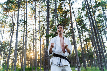 A young guy doing karate training and meditation in the forest during the day