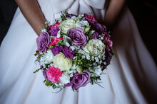 Close-Up Of A Bride Holding A Bunch Of Pink, Purple And White Flowers