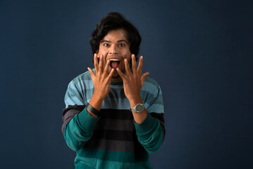 Wall Mural - Young handsome man over dark background afraid and shocked with surprise and amazed expression, fear and excited face.